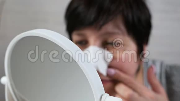 女性步入老年照镜子用手摸脸在家打理肌肤美容理念抗衰老视频的预览图