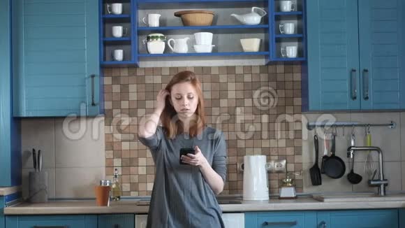 女孩在厨房里喝早咖啡女人在智能手机上写信息视频的预览图
