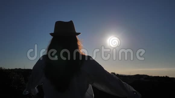 女人站在上面看着在黎明时举起双手向太阳看视频的预览图