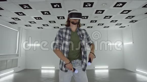 虚拟现实耳机中的年轻人在一个充满白色霓虹灯照明的空玩室里用视频游戏跳舞视频的预览图