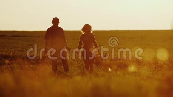 农民日落时一男一女穿过田野带着一棵树苗一个浇水罐和一把铲子视频的预览图