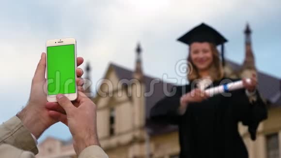 手机上的一张照片上面是一位刚刚获得硕士学位年轻女子的空白屏幕视频的预览图