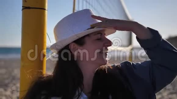 戴帽子的快乐女人站在海滩上四处张望视频的预览图