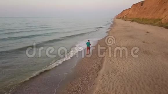 日落时沿着海滩散步的人视频的预览图