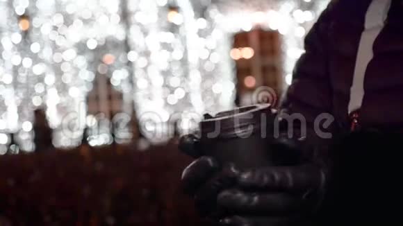 女人戴着手套的手拿着塑料杯带着一杯银色的饮料视频的预览图
