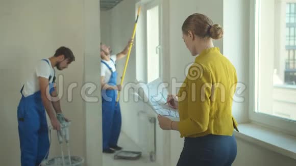 女人看着建筑工人如何工作并修改图纸视频的预览图