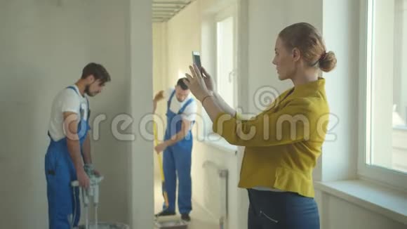 女人打电话拍照修理工在公寓工作视频的预览图