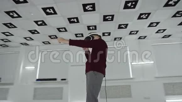 穿着棕色毛衣的小男孩在空玩室里戴着耳机用手在虚拟现实中射击视频的预览图