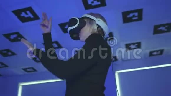 成年女性站在虚拟现实耳机里在一个充满闪烁霓虹灯的房间里做手势视频的预览图