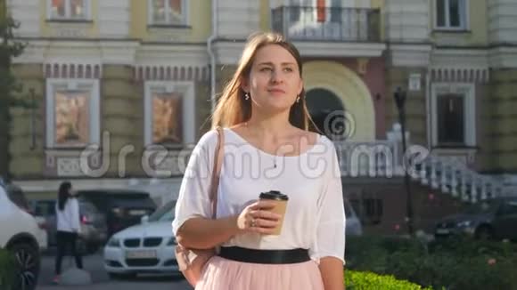4k慢动作视频快乐微笑的女人留着长发在办公室休息时喝咖啡然后继续走视频的预览图