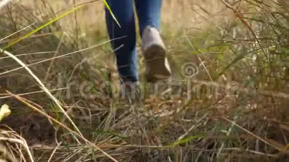 4k视频从低角度看年轻女子穿着运动鞋走在道路上穿过高高的草地视频的预览图