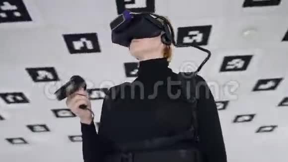成年女性站在虚拟现实耳机里手持一个带有白色的大空厅的控制器视频的预览图