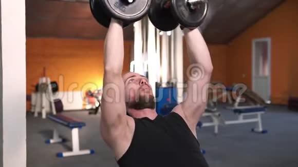 强壮的男人在体育俱乐部举重特写男在健身房用哑铃训练肌肉视频的预览图