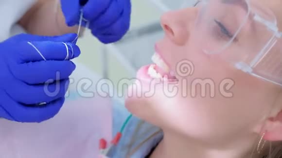 牙医在牙科特写镜头中使用牙线清洁女性患者牙齿视频的预览图