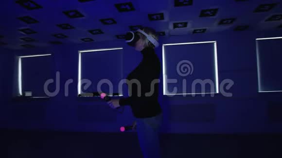 虚拟现实耳机里的年轻女子拿着控制器站在一个充满红色眨眼的空玩室里视频的预览图