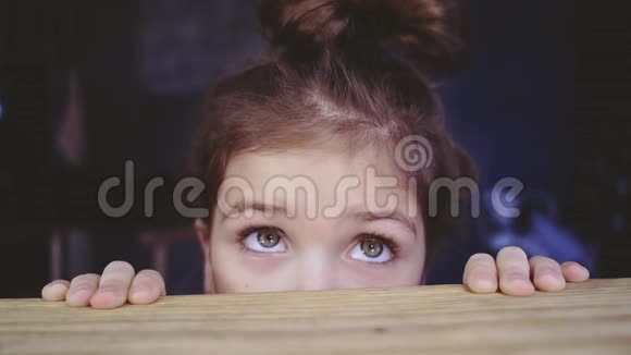 有趣的女孩从桌子上偷窥秘密藏身之处可爱的小孩子躲在桌子下面小女孩躲起来视频的预览图