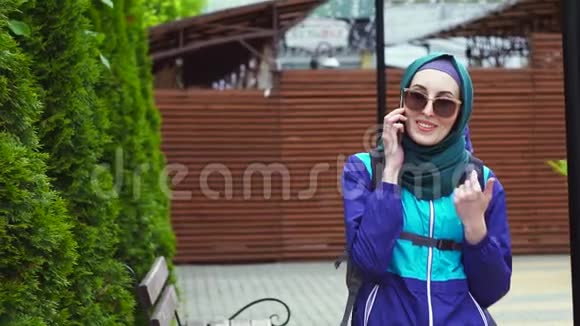 一位戴头巾戴墨镜背包的女游客在电话中交谈的肖像视频的预览图