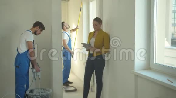 女人拿着平板电脑走路看建筑工人如何工作视频的预览图