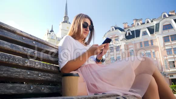 特写4k低角度视频年轻女性在智能手机上打字或浏览互联网而坐在长凳上视频的预览图