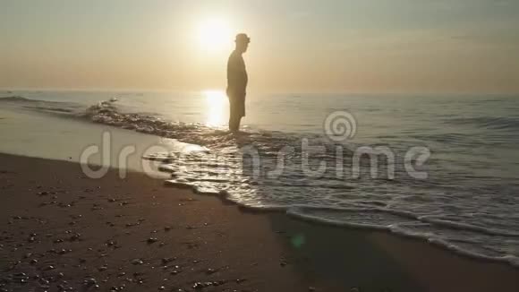 日出时人们平静地沿着一片荒芜的海滩散步一个人沿着一个逃兵平静地走着视频的预览图