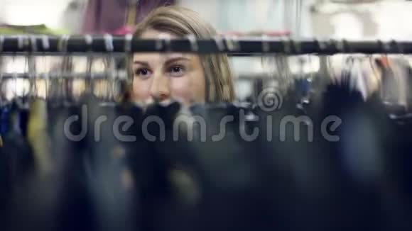 年轻有魅力的女人正在商场的服装店里检查衣架微笑着视频的预览图