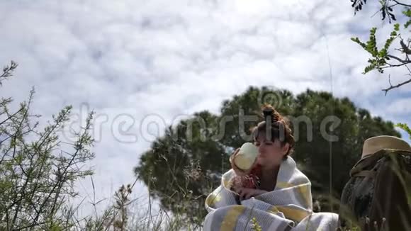 旅行妇女端着杯子坐在大自然中喝着饮料享受着早晨的乐趣野营视频的预览图