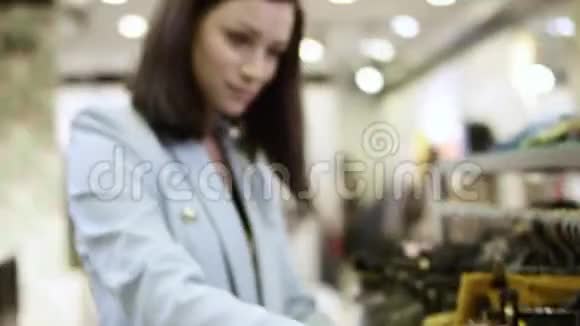 在商场的一家服装店里一位年轻漂亮的女士正在寻找服装她正在寻找价格和视频的预览图