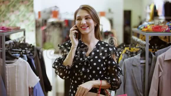 快乐年轻迷人的女人在智能手机上聊天在商场的服装店微笑视频的预览图