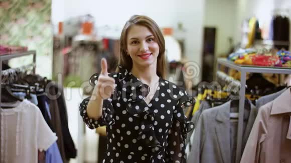 快乐的年轻迷人的女人在商场的服装店展示拇指手指视频的预览图