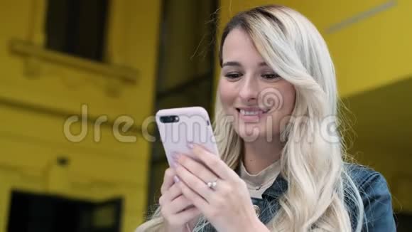 女人在城市里散步户外使用智能手机漂亮的时髦女郎学生女孩在智能手机上发短信和使用应用程序视频的预览图