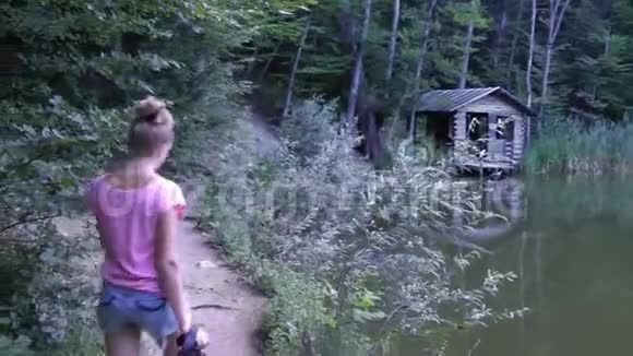 带着相机的女孩在森林里的湖边散步视频的预览图