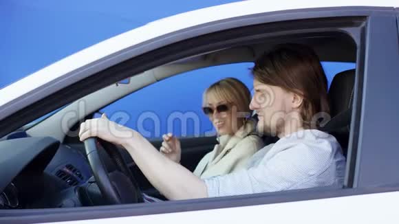 有趣的黑发男人和开朗的金发女人正在享受汽车旅行他们在听音乐唱歌跳舞视频的预览图