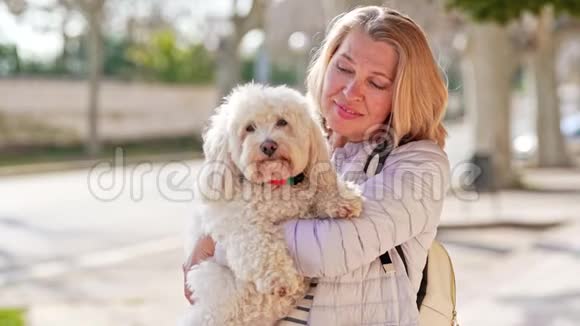 夏天城里的中年妇女带着毛茸茸的白狗散步视频的预览图