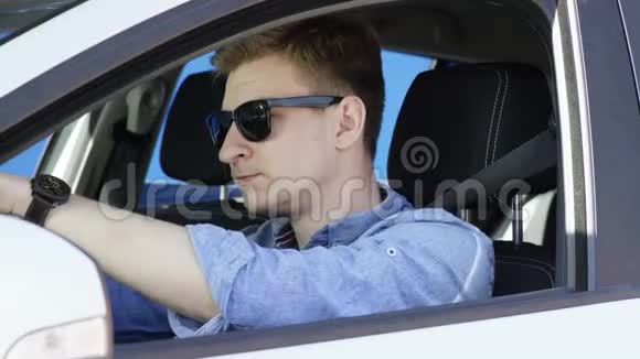 年轻人在交通堵塞中很累他把头放在方向盘上坐在白色的蓝屏车上视频的预览图
