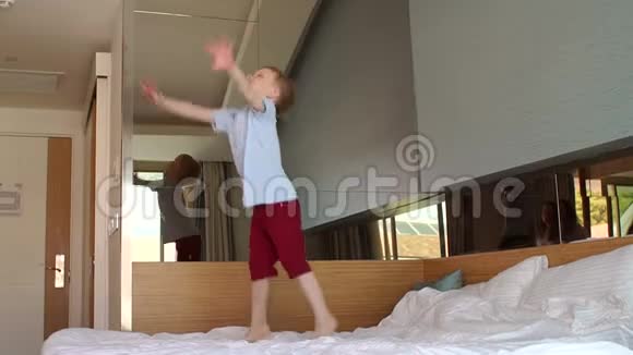 快乐的孩子5岁带着镜子在卧室的床上跳跃视频的预览图