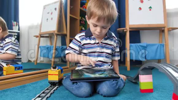 4K小男孩坐在铺有玩具的地毯上的卧室里玩数字游戏的录像视频的预览图