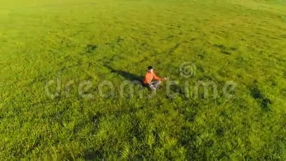 低空径向飞行超过运动瑜伽男子在完美的绿草在山上日落视频的预览图