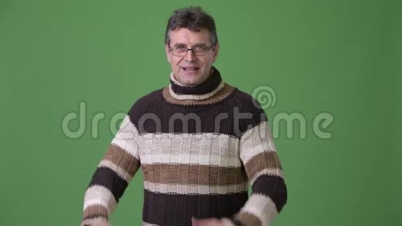 成熟的帅哥穿着绿色背景的高领毛衣视频的预览图