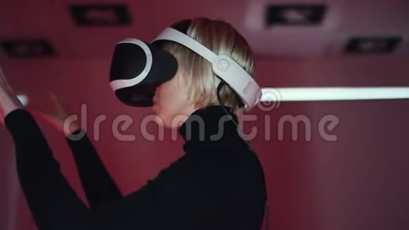 一个年轻女子在虚拟现实耳机中近距离拍摄她在一个游戏室里的网络空间里做手势视频的预览图