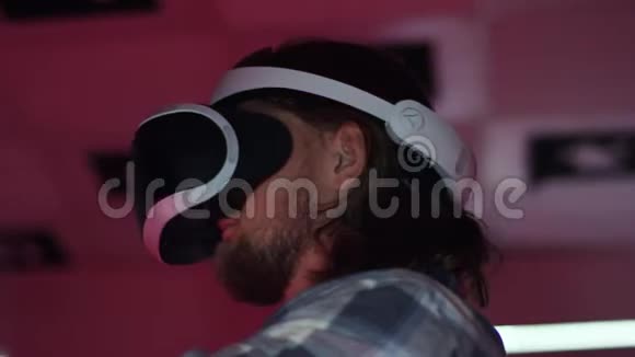 近距离追踪一个年轻人戴着虚拟现实耳机和控制器握手360度镜头视频的预览图