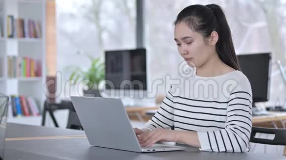 在咖啡馆里用笔记本电脑咳嗽的年轻亚洲女人视频的预览图