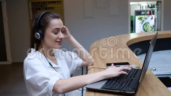 女学生使用笔记本电脑和互联网进行培训戴着耳机的年轻女子视频的预览图