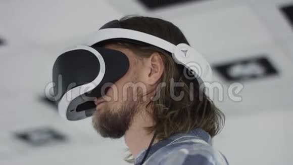 近距离跟踪弧360度拍摄的一个年轻人戴虚拟现实耳机和使用控制器白色霓虹灯视频的预览图