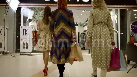 三个女人拿着购物袋走在商场的服装店视频的预览图