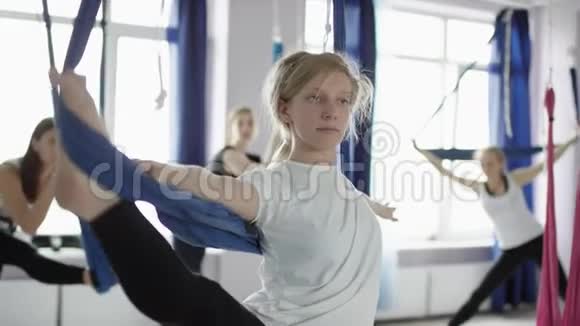 女子吊床瑜伽课一群妇女在健身房里做伸展运动视频的预览图