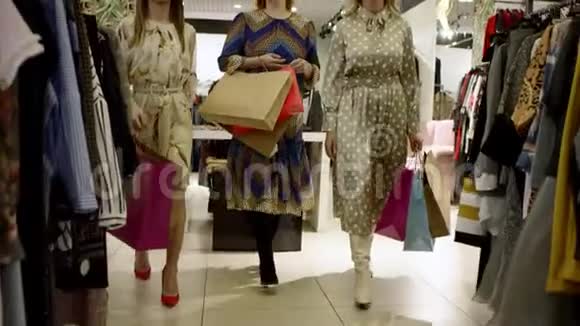三个快乐的漂亮女人正在购物中心的服装店里微笑着交谈视频的预览图