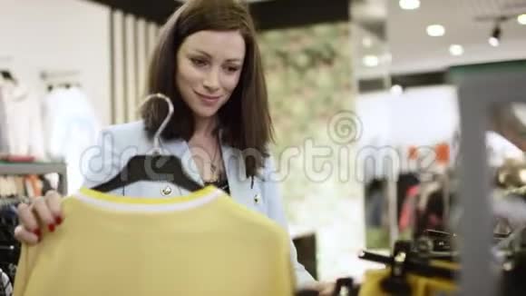 在商场的一家服装店里一位年轻漂亮的女顾客正在检查一件衬衫把它放好视频的预览图