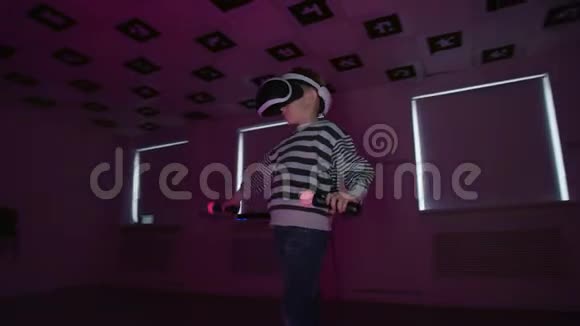 小男孩正在虚拟现实中玩电子游戏在房间里戴着耳机闪烁着霓虹灯追踪着弧线视频的预览图