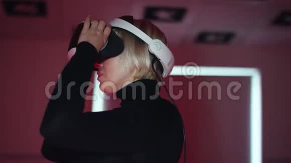 一个年轻女子的特写镜头她戴着一个虚拟现实耳机把它摘下来摸了摸然后戴在一个视频的预览图