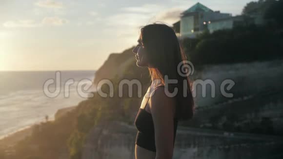 女人看着她在祈祷的海洋日落背景4k视频的预览图